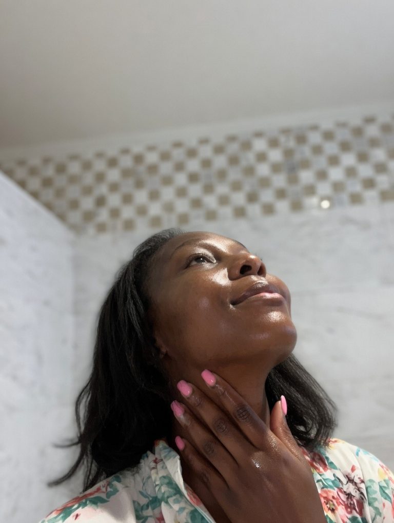 Black woman applying cream to neck