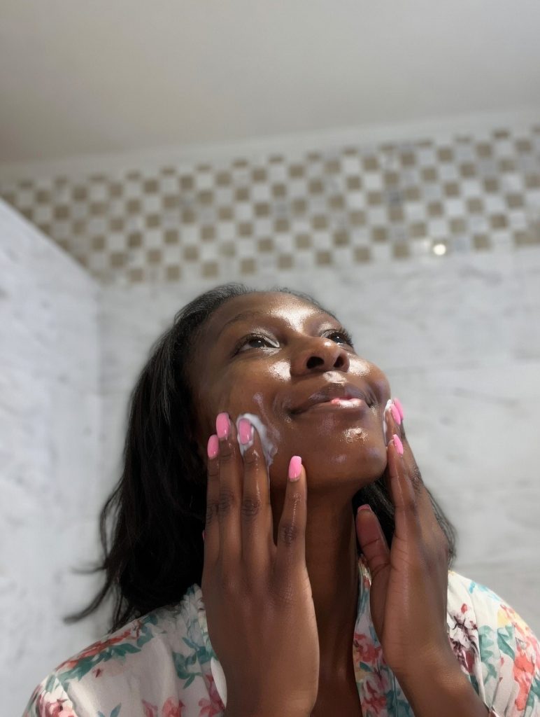 Black woman applying facial cleanser